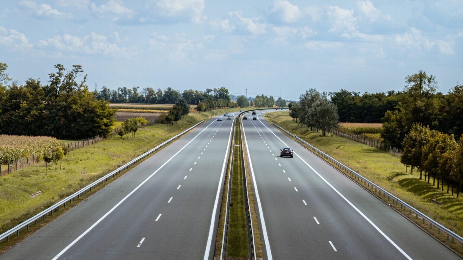 To motorveje ved siden af hinanden med en skyet let blå himmel